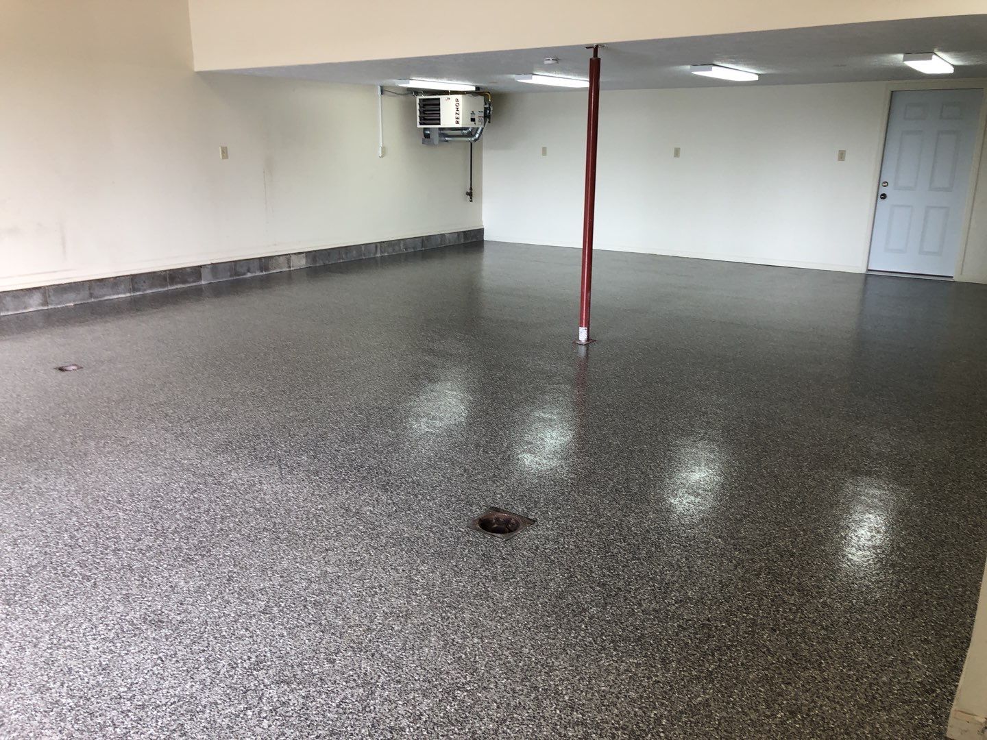 Dark gray flake garage floor with a support post and white walls